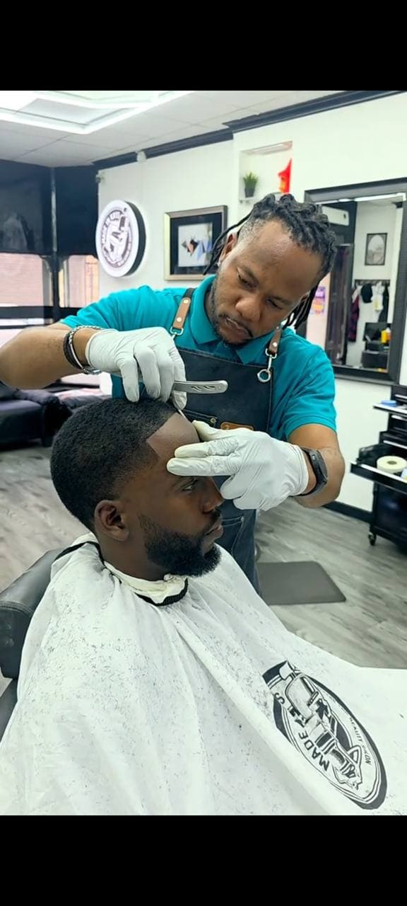 Barber lining up a client's fade with a straight razor